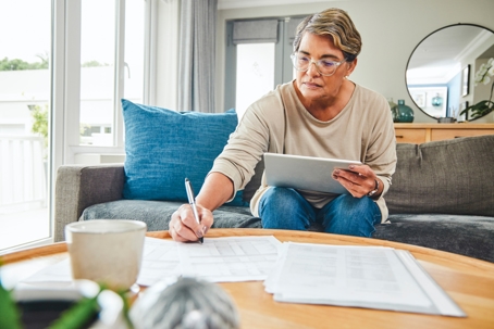 older woman browsing documents and writing notes