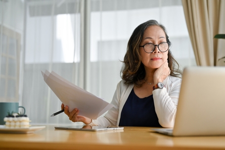 woman reviewing documents while looking at a laptop