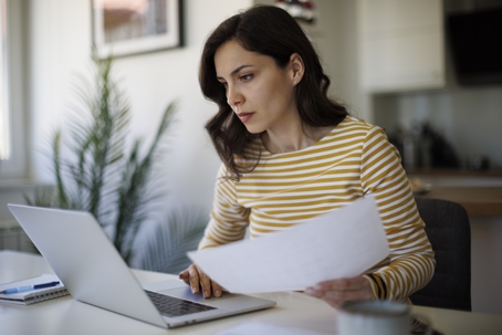 woman reviewing documents while on the computer
